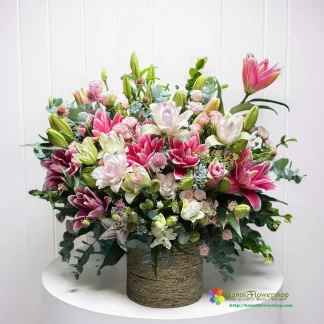 Mixed pink and white lily flower arrangement in a basket